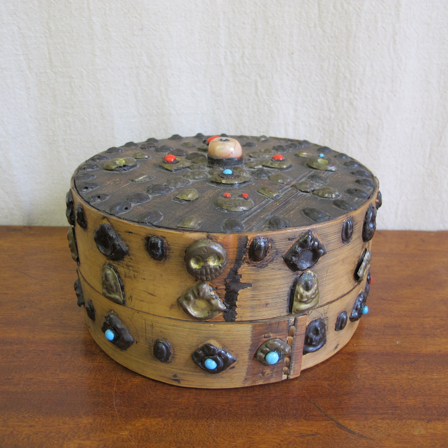 19th century Tibetan Buddhist bentwood box with applied brass relief panels (skulls, seated Buddhas) and glass representing turquoise and coral