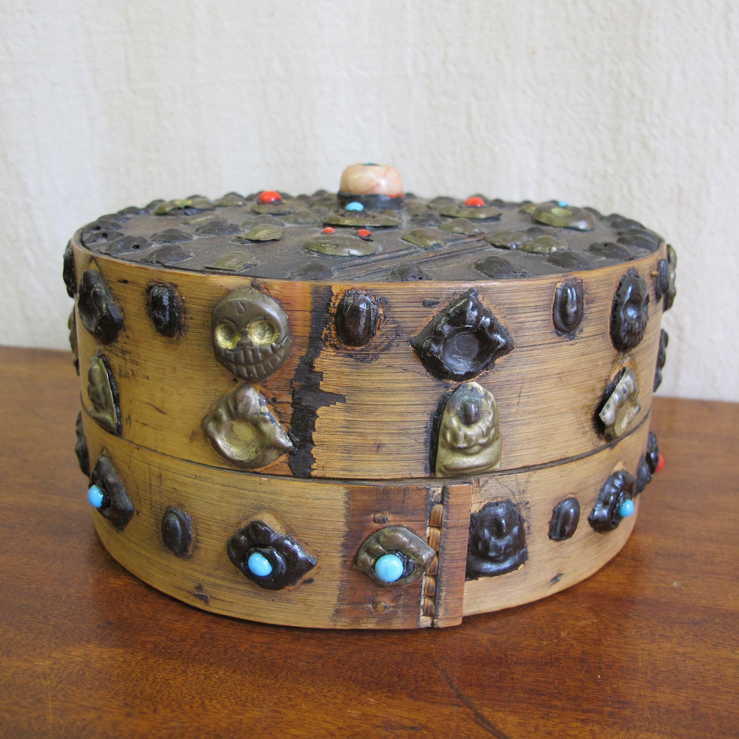 19th century Tibetan Buddhist bentwood box with applied brass relief panels (skulls, seated Buddhas) and glass representing turquoise and coral