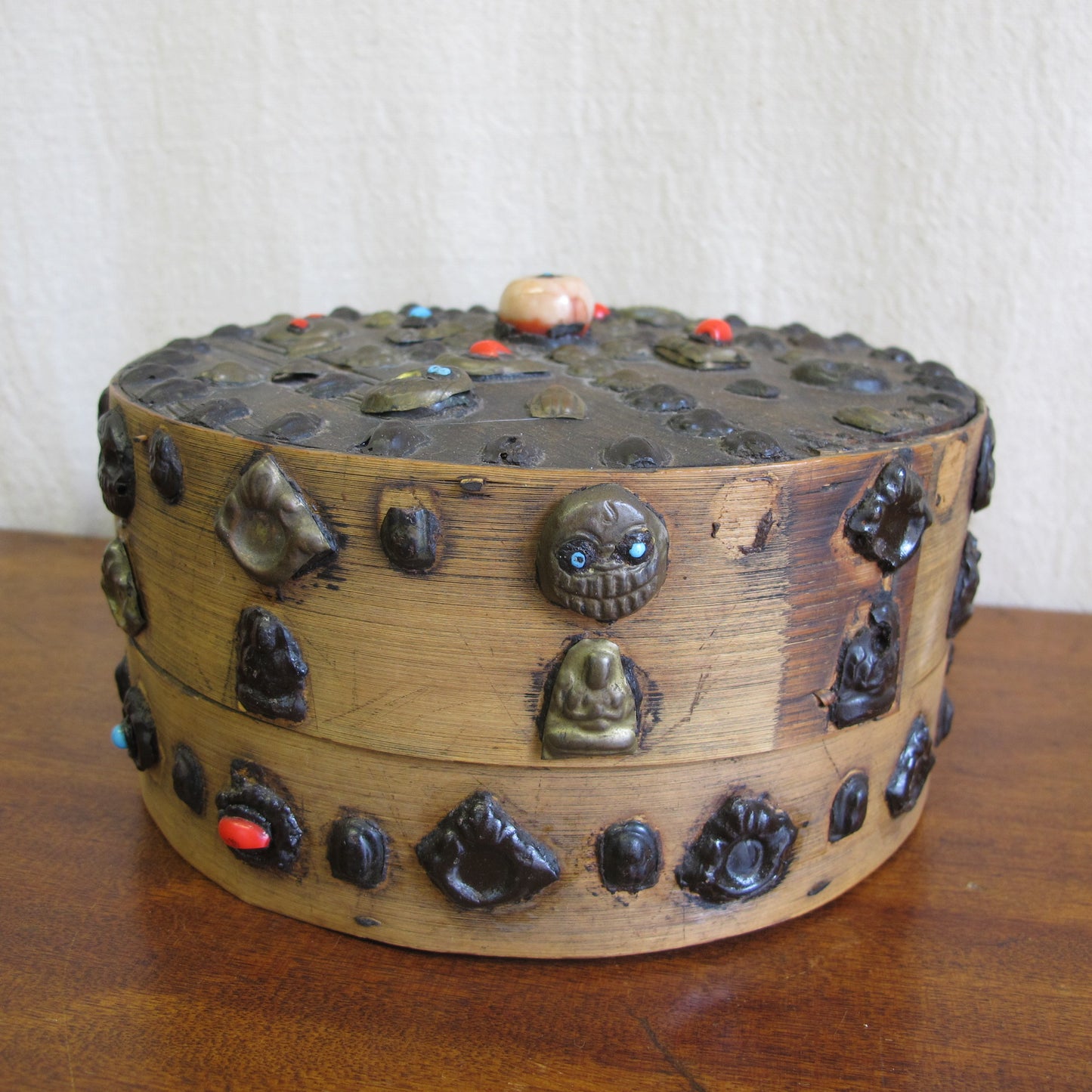 19th century Tibetan Buddhist bentwood box with applied brass relief panels (skulls, seated Buddhas) and glass representing turquoise and coral