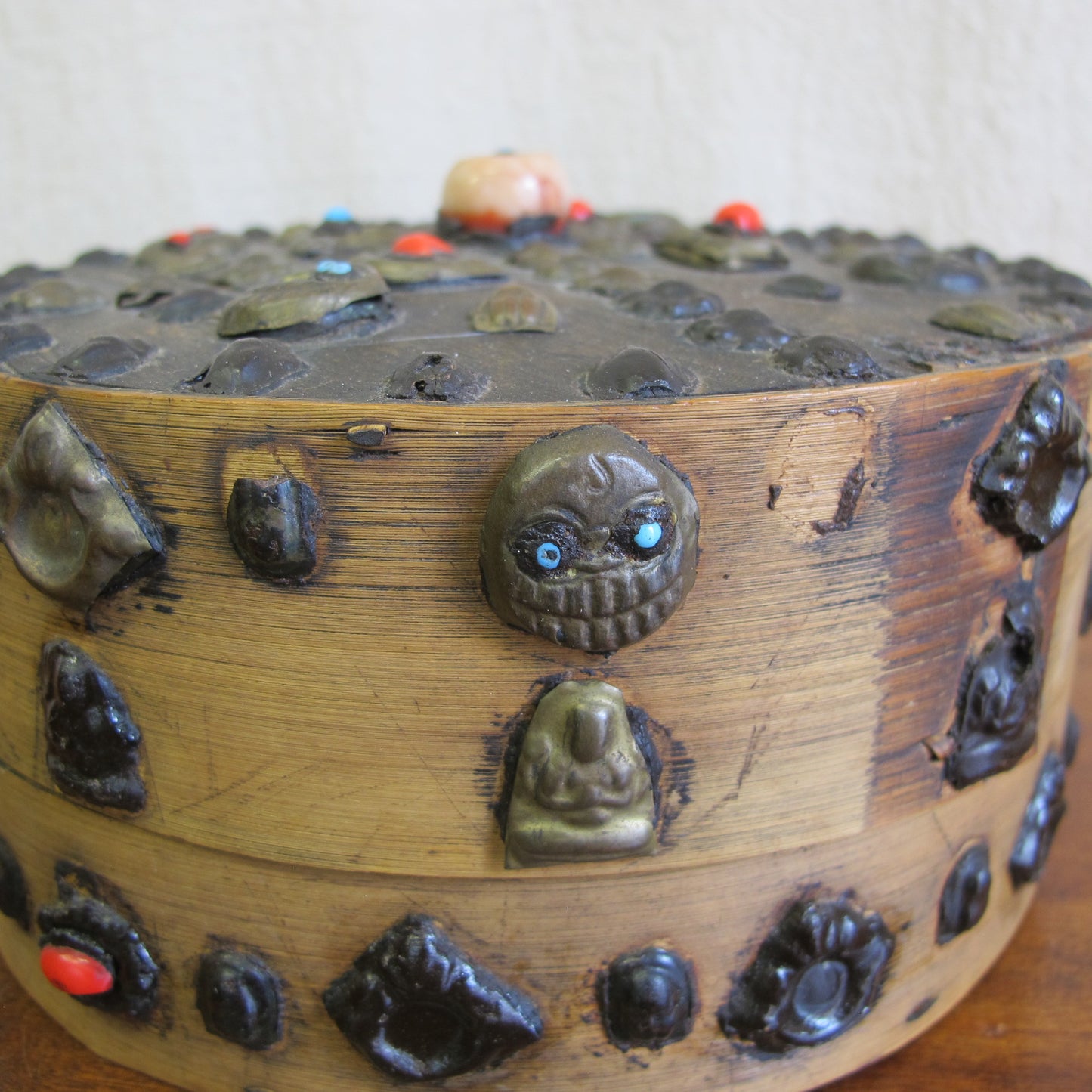 19th century Tibetan Buddhist bentwood box with applied brass relief panels (skulls, seated Buddhas) and glass representing turquoise and coral