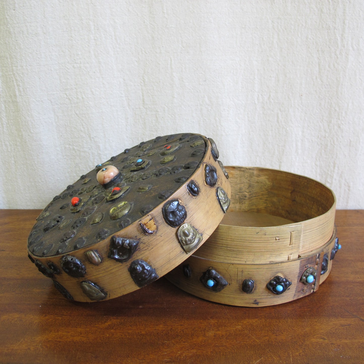 19th century Tibetan Buddhist bentwood box with applied brass relief panels (skulls, seated Buddhas) and glass representing turquoise and coral